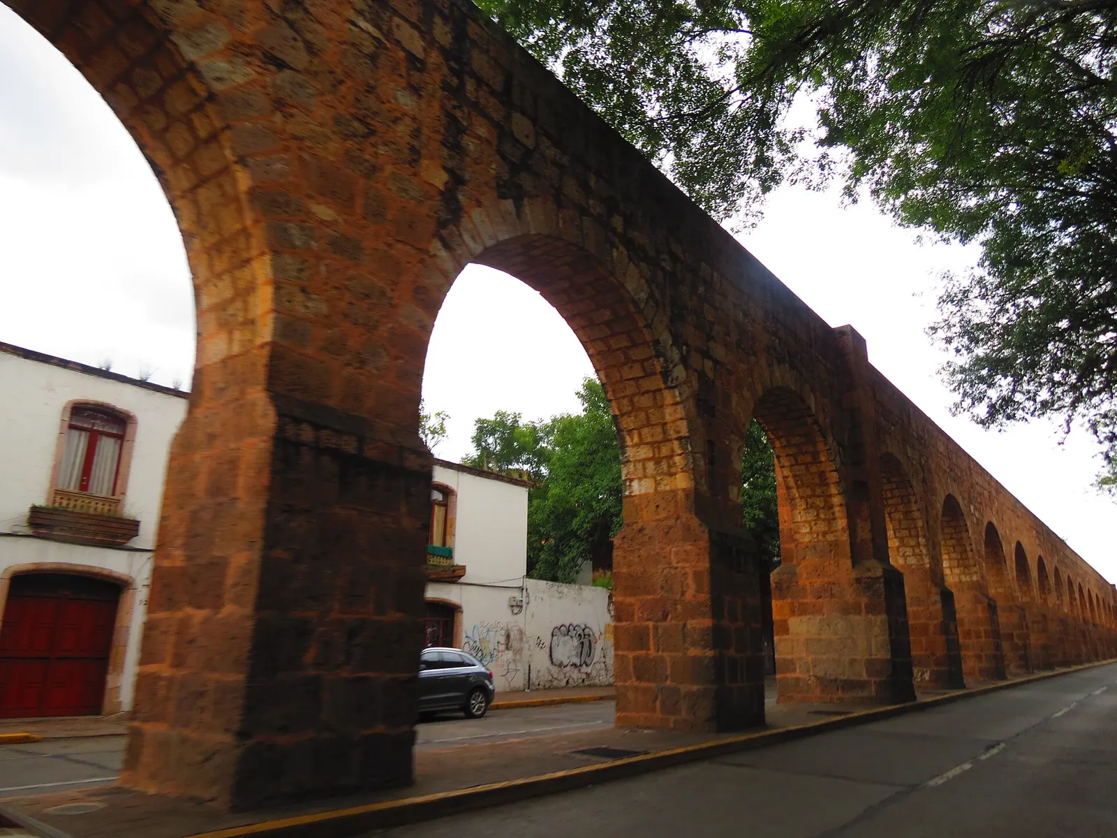 Los arcos de cantera del acueducto de Morelia junto a una calle de casas